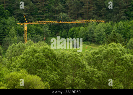 Grande costruzione gialla gru installato nel mezzo della foresta verde Foto Stock