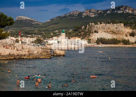 La gente di nuoto sulla spiaggia, Plage Le Bestouan, sullo sfondo il faro di Cassis, Bouches-du-Rhone, Provence-Alpes-Côte d'Azur, southern Fr Foto Stock