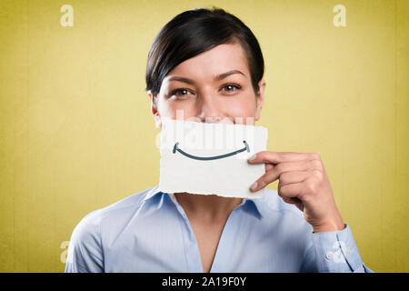 Sorridente imprenditrice azienda blank carta bianca nella parte anteriore della sua bocca. Foto Stock