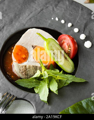 Pesce bollito con verdure sul tavolo Foto Stock