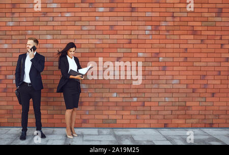 Gli imprenditori stand su un muro di mattoni dello sfondo. Concetto di lavoro business professional meeting. Foto Stock