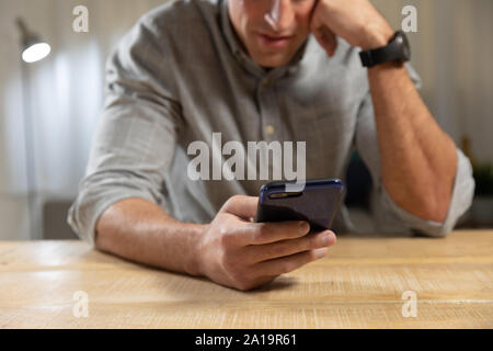 Giovane uomo di casa utilizzando uno smartphone Foto Stock