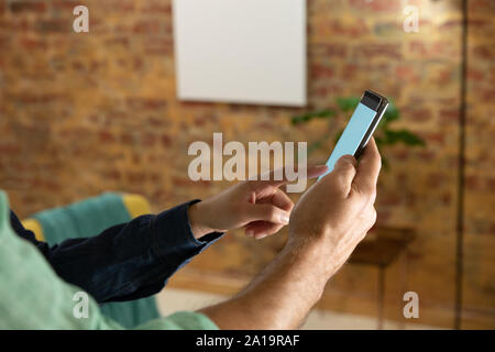 Coppia giovane di casa utilizzando uno smartphone Foto Stock