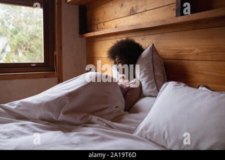 Giovane donna utilizza lo smartphone nel letto Foto Stock