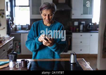 Senior donna utilizza lo smartphone a casa Foto Stock