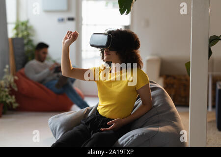 Giovani femmine creative in VR auricolare in un ufficio Foto Stock