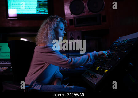 Femmina produttore musicale il lavoro presso il banco di miscelazione in un sound studio Foto Stock