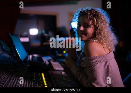 Femmina produttore musicale il lavoro presso il banco di miscelazione in un sound studio Foto Stock