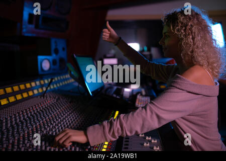 Femmina produttore musicale il lavoro presso il banco di miscelazione in un sound studio Foto Stock