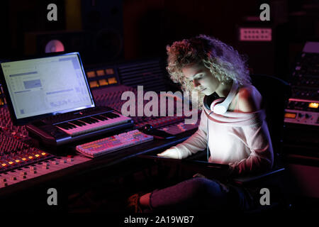 Femmina produttore musicale lavorando in un sound studio Foto Stock