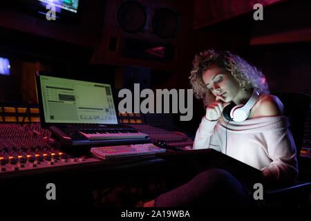 Femmina produttore musicale lavorando in un sound studio Foto Stock