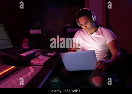 Maschio produttore musicale lavorando in un sound studio Foto Stock