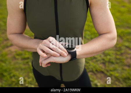 Giovane donna orologio di controllo in una palestra a cielo aperto bootcamp Foto Stock