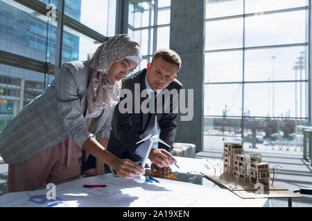 Maschio e femmina architetti discutendo su blueprint in office Foto Stock