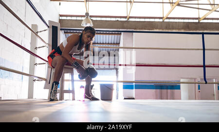 Boxer femmina rilassante nel pugilato ring al centro fitness Foto Stock