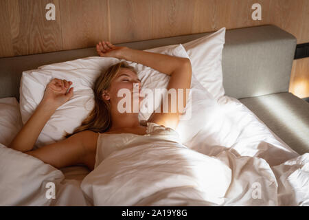 Giovane donna bionda che dorme nel letto Foto Stock