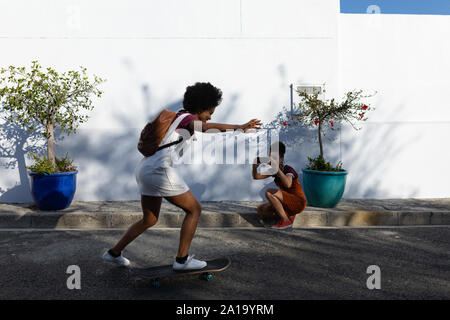 Giovane donna cavallo su skateboard in strada Foto Stock