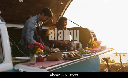 Giovani razza mista giovane impegnato a preparare il cibo in stallo Foto Stock