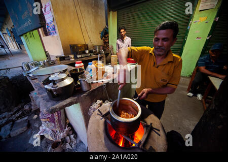 Uomo indiano la preparazione di cibo in un tipico cibo di strada in stallo Rudraprayag town, Uttarakhand, India Foto Stock