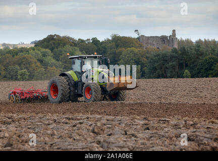 Claas Axion 850 operando a nuova Farm Ladykirk sulla frontiera scozzese con il castello di Norham appena oltre il Tweed in Inghilterra. Foto Stock