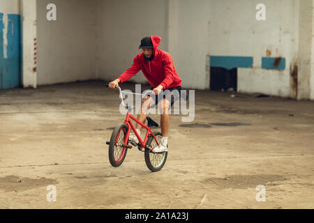 Il pilota di BMX in un magazzino vuoto Foto Stock