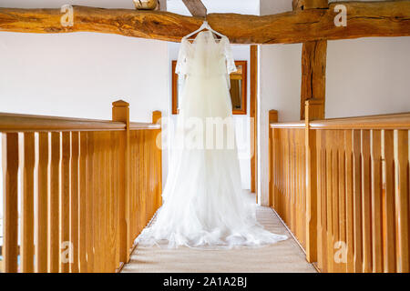 Un spose abito da sposa appeso a una quercia trave di legno sul pianerottolo Foto Stock