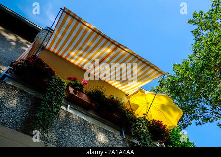 Brunswick, Germania. 24 Ago, 2019. Un giallo e bianco Tenda a strisce e un ombrellone giallo ombra di un balcone da un cielo blu. Credito: Stefan Jaitner/dpa/Alamy Live News Foto Stock