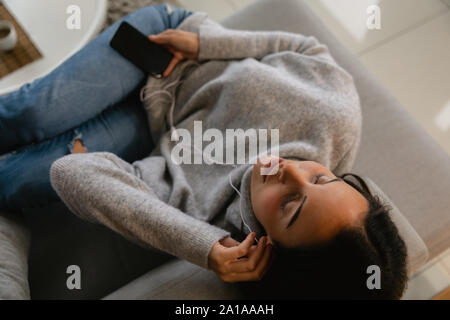 Bruna giovane donna ascoltando la musica con gli auricolari Foto Stock