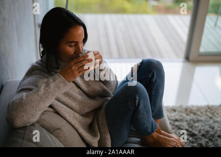 Bruna giovane donna di bere il caffè Foto Stock