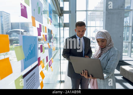 La gente di affari lavorando su laptop vicino a parete in vetro in office Foto Stock