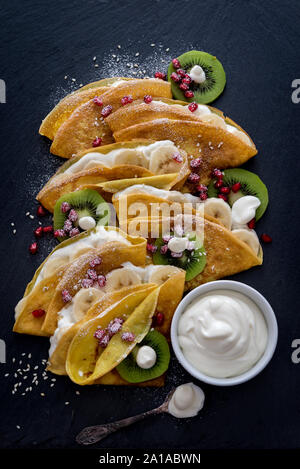 Crespelle sottili con il cioccolato fuso, i semi di sesamo, melograno e mandorle Foto Stock