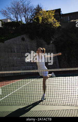 Donna che gioca a tennis in una giornata di sole Foto Stock