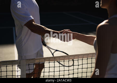 La donna e l uomo si stringono la mano a un campo da tennis Foto Stock