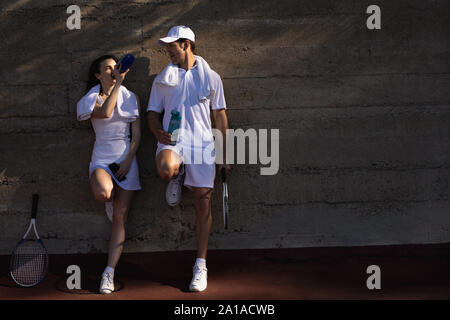 Donna e uomo prendendo una pausa durante una partita di tennis Foto Stock