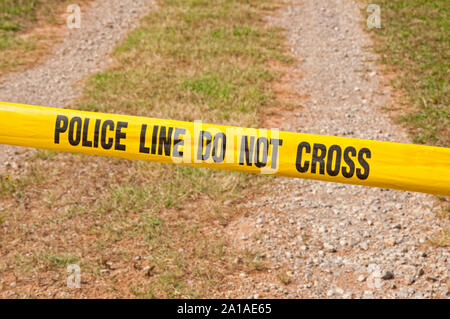 Linea di polizia non cross - nastro di segnalazione attraverso la ghiaia rurale carreggiata Foto Stock