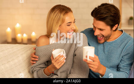 I coniugi ridere di bere il caffè seduti sul divano Foto Stock