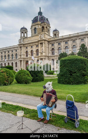 Uomo che indossa il cavallo di acconciatura di suonare la fisarmonica a piano nella parte anteriore del Kunsthistorisches Museum di Vienna, Austria. Foto Stock