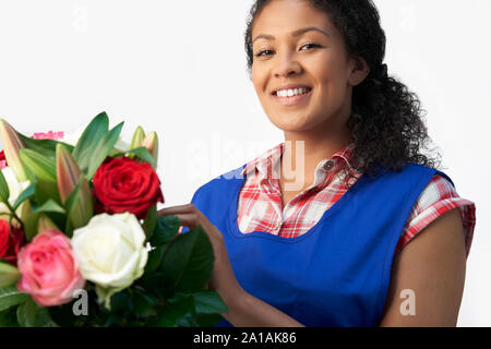 Ritratto di femmina disponendo di fiorista bouquet di Lillies e rose contro uno sfondo bianco Foto Stock