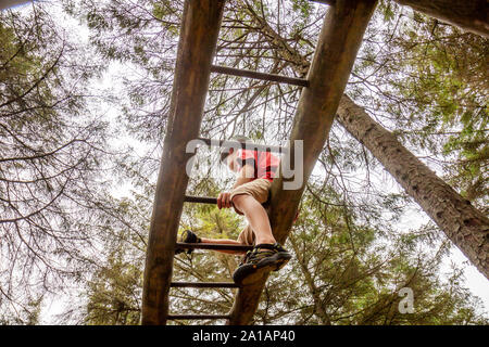 Felice ragazzo divertirsi salendo sulla scaletta nella foresta. Foto Stock