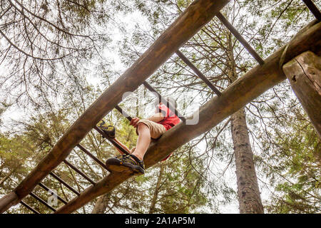 Felice ragazzo divertirsi salendo sulla scaletta nella foresta. Foto Stock