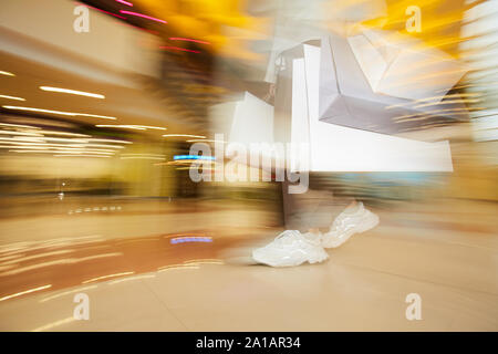 Moto sfocata del cliente a piedi lungo il negozio con i sacchi di carta dopo lo shopping Foto Stock