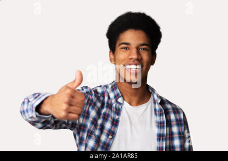 Overjoyed ragazzo africano che mostra il pollice fino a studio Foto Stock