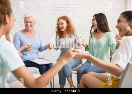 Sorridente Diverse donne seduti in cerchio durante la terapia di gruppo Indoor Foto Stock