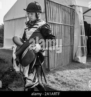 Jockey indossando sete sella portante dopo la Gara di jump Foto Stock