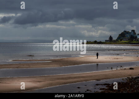 Spiaggia e uomo in presenza di luce solare a whiting bay su arran Foto Stock