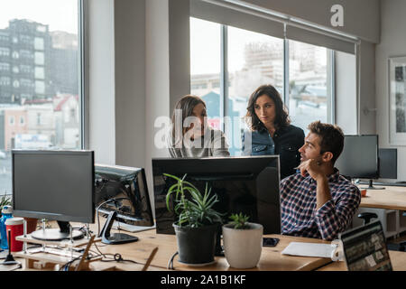 Diversi gruppi di giovani progettisti che lavorano su un computer insieme Foto Stock