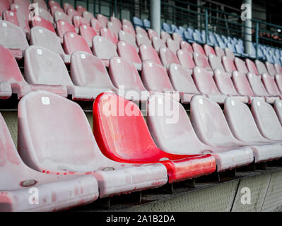 Enfasi su una sedia a differenza tra le file di sedili in gabbie vuote dello stadio Foto Stock