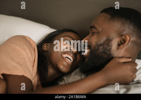 Affettuosa giovane americano africano giovane ridere insieme a letto Foto Stock