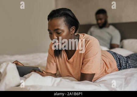 Giovane americano africano donna giaceva a letto utilizzando un tablet Foto Stock