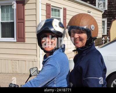 Mamma e figlia condividi scooter in Lavallette, New Jersey .Mom è un tempo di due superstite. Fine della stagione estiva consente il facile passo sicuro. Elegante caschi. Foto Stock